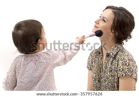 little girl putting on the makeup to her mother Royalty-Free Stock Photo #357957626