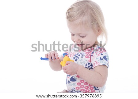 toddler girl brushing duck teeth, isolated on white