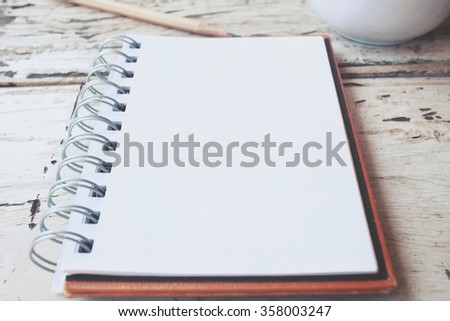 Blank notepad and pencil with latte art coffee on office table