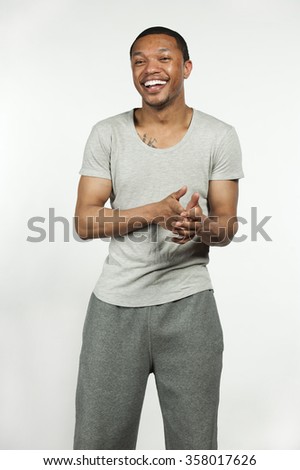 A happy attractive African American male wearing a sweatshirt with sweatpants posing in a studio setting on a white background.