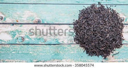 Dried black tea leaves over wooden background
