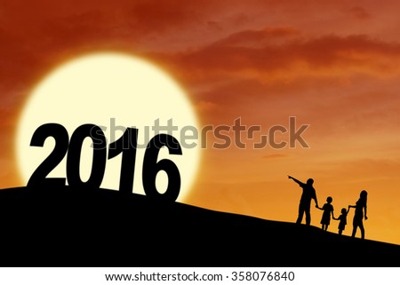 Silhouette of happy family walking on the hill while holding hands with numbers 2016, shot at sunset time
