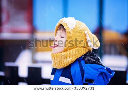 Cute little boy, playing with snow in the park, playground, wintertime