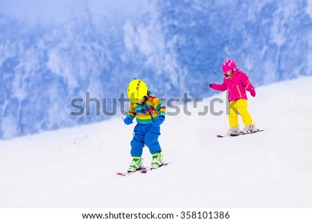 Children skiing in the mountains. Toddler kids in colorful suit and safety helmet learning to ski. Winter sport for family with young child. Kid ski lesson in alpine school. Snow fun for little skier.