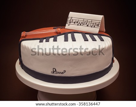 Birthday cake decorated with fondant, rounded, symbolically presenting piano and cello instruments. 