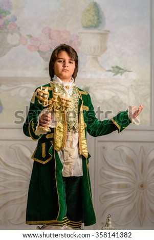 Boy stands in vintage clothes with candlestick in hands