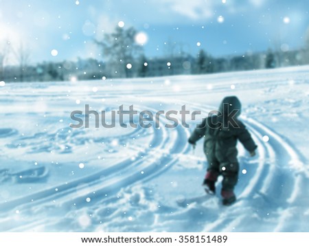 A child in a suit running on the track of snow traces of the wheels of cars cold cold winter day in the country.