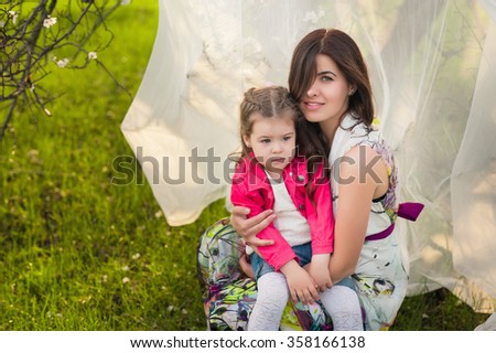 Mom hugs kisses daughter in the lush spring garden, the family, motherhood, spring,