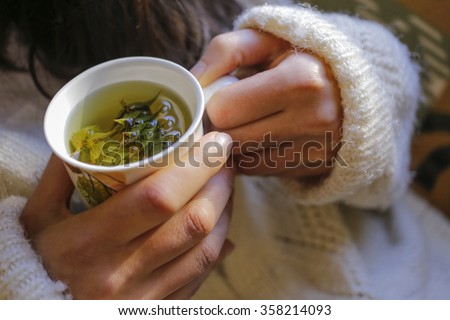 The young woman on the couch and with sage tea on the hand. Royalty-Free Stock Photo #358214093