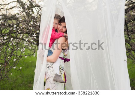 Mom hugs kisses daughter in the lush spring garden, the family, motherhood, spring,