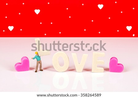selective focus of miniature worker holding wood text with heart candle,abstract background to valentine concept.
