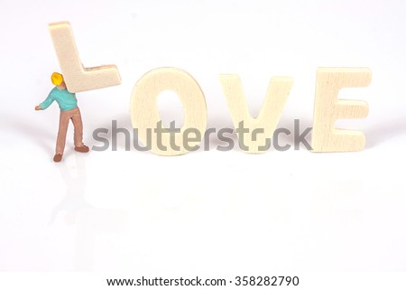 selective focus of miniature worker holding wood text love,abstract background to valentine concept.
