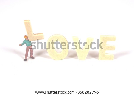 selective focus of miniature worker holding wood text love,abstract background to valentine concept.vintage tone.