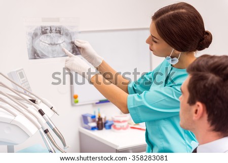 Dentist Doctor keeps in the hands of X-ray picture of the human jaw, analyzing it with the patient