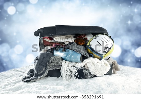 snow trip time and clothes in open suitcase 