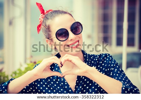 Love you. Portrait close up happy smiling young woman showing heart sign gesture with hands isolated restaurant coffee shop background. Positive human emotion expression feeling attitude body language