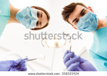 Doctor and dentist assistant, protection gloves, using dental tools, a mask looking at the camera. Close-up Royalty-Free Stock Photo #358331924