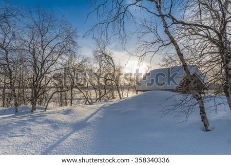 Snow Covered House and bare trees on field during sunrise
