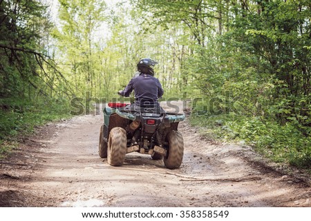 Man on the ATV Quad Bike on the mountains road.  Royalty-Free Stock Photo #358358549