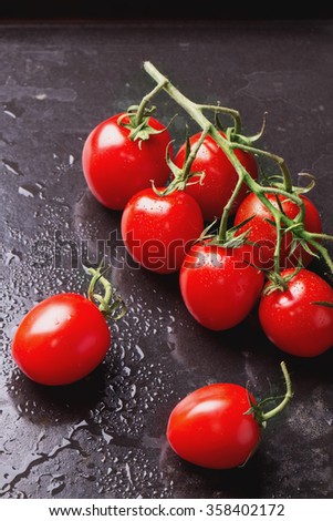 Variety of different tomatoes: red, orange, yellow and cherry on the cutting board and black metal tray