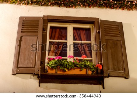 A window with open shutters beds with red curtains