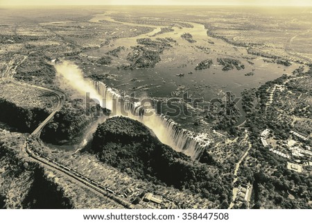 The Victoria falls is the largest curtain of water in the world. The falls and the surrounding area is the National Parks and World Heritage Site (helicopter view) - Zambia, Zimbabwe (stylized retro)