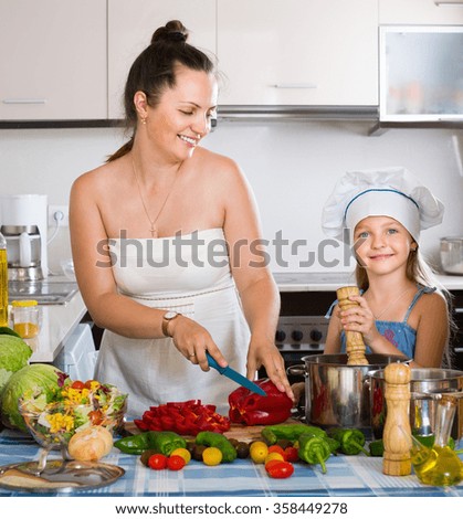 Happy woman and her daughter cooking healthy dinner