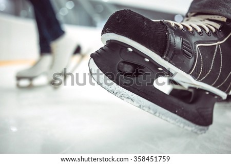Man's hockey skates and women's figure skates on ice background