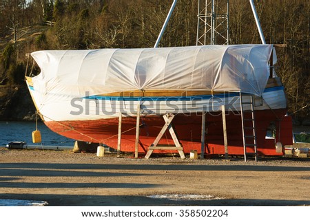 Boats in winter storage covered with tarps and supported by scaffolding. Winter storage on land protects the boats from the sea ice that could otherwise cause damage to the keels. Royalty-Free Stock Photo #358502204