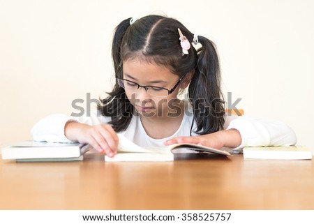 School education and literacy concept with Asian girl kid student learning hard and reading book in library or classroom