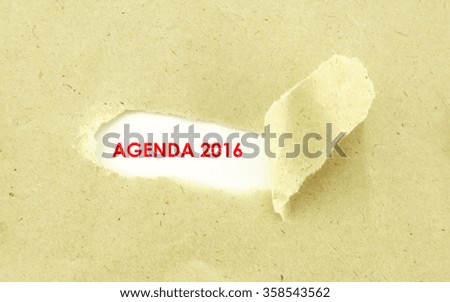 Text AGENDA 2016 appearing behind torn light brown envelop
