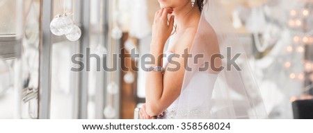 valentine's day, bridal, wedding, christmas, x-mas, winter, happiness concept - bride looking at window. Royalty-Free Stock Photo #358568024