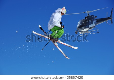 a skier in green and white performing a tele-heli, being filmed from a crew in a helicopter equipped with a front mounted steady cam Royalty-Free Stock Photo #35857420
