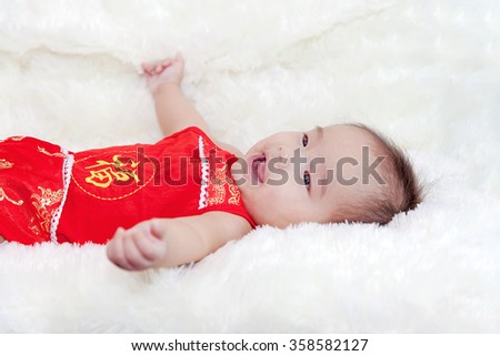 Cute five months asian baby smiling in red cheongsam., on bright soft carpet., Chinese character is "Fu" means Luck and Good Fortune.