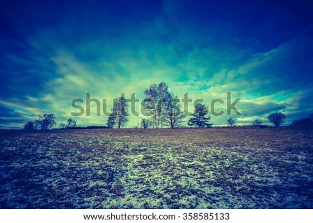 Vintage photo of early winter or late autumnal landscape of field at good weather. Fields with little snow.