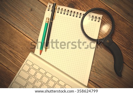 Computer keyboard, notebook, magnifying glass and a pencil with a ballpoint pen on the desk of the old boards. Internet search. instagram image filter retro style