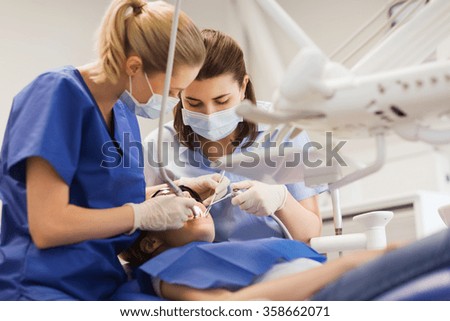 female dentists treating patient girl teeth Royalty-Free Stock Photo #358662071