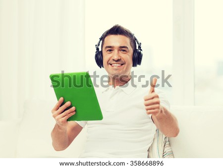 smiling man with tablet pc and headphones at home