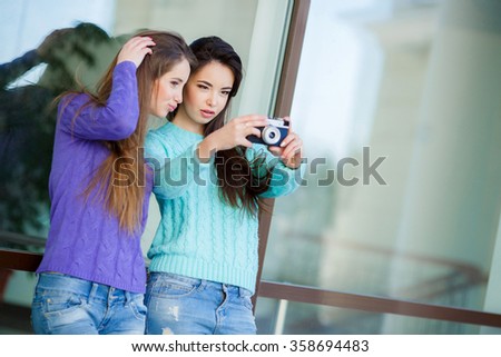 Cute pretty girls making funny selfie on the street, kissing to the cheek, having fun together, joy, positive, love, friendship, sisters.Girlfriends Taking Self Portrait with Their Phone Camera 