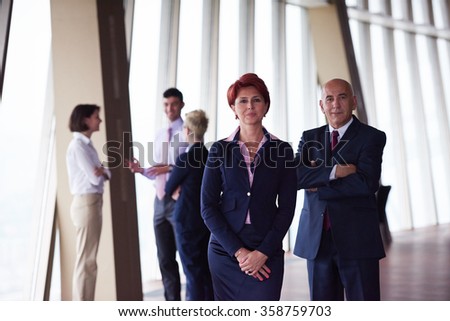 diverse business people group standing together as team  in modern bright office interior  with redhair senior woman in front as leader
