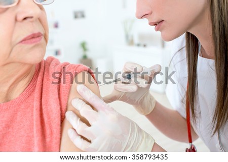 Injection in her shoulder Royalty-Free Stock Photo #358793435