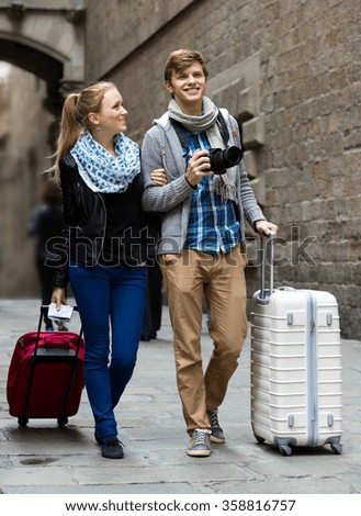 Young husband and smiling woman with photo camera studying neighborhood