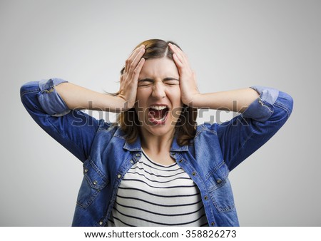 Portrait of a stressed woman holding head in hands Royalty-Free Stock Photo #358826273