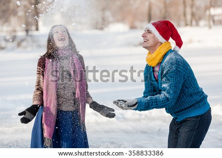 Happy couple having fun ice skating on rink outdoors. Throwing snow together. Winter sport and leisure concept. Love and fun in wintertime.