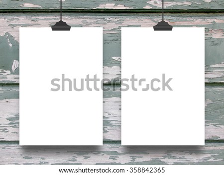 Close-up of two hanged paper sheets with clips on scratched wooden boards background