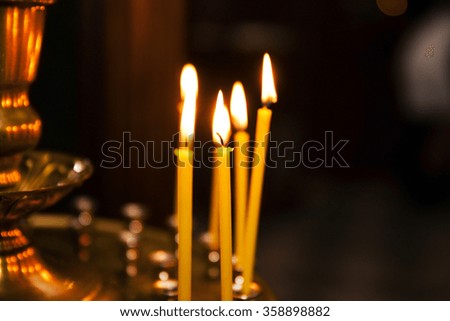  a lighted candle on a candlestick in the church. Photographed close-up.
