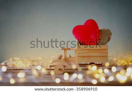 low key and double exposure photo of wooden toy truck with hearts. valentine's day celebration concept. vintage filtered