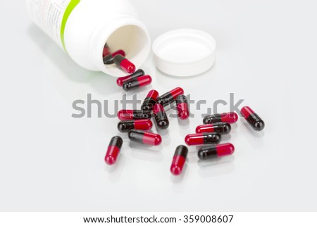 black & red pills an pill bottle on white background