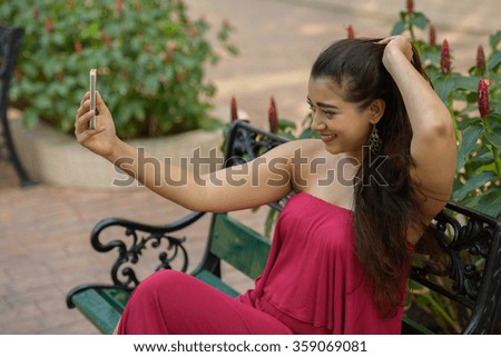 Woman outdoors in park taking selfie with mobile phone