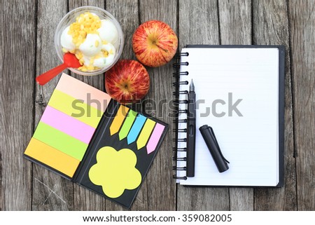 Workspace with notebook, ice cream and apple on the wooden table